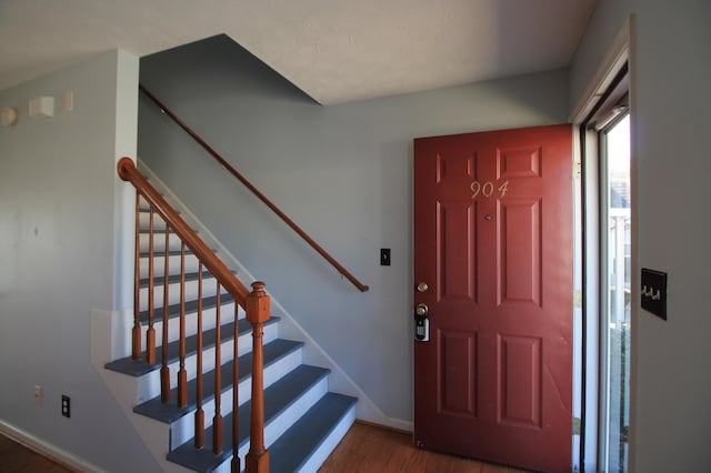 foyer with baseboards, wood finished floors, and stairs