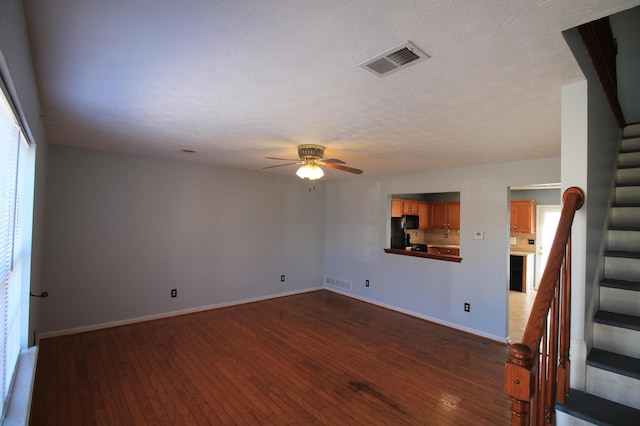 spare room with dark wood-style floors, visible vents, stairway, and ceiling fan