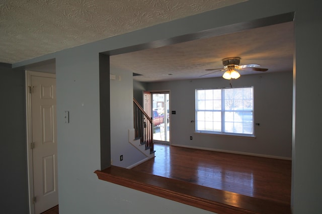 interior space featuring stairway, wood finished floors, baseboards, and a textured ceiling