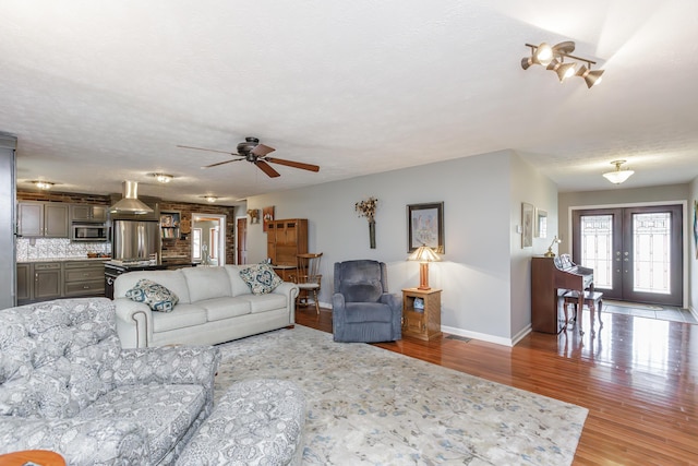 living area featuring visible vents, baseboards, light wood-type flooring, french doors, and a ceiling fan