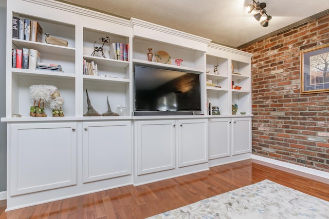 unfurnished living room with brick wall and light wood-style floors