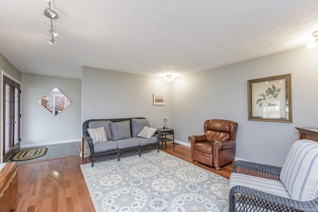 living room featuring a textured ceiling, baseboards, and wood finished floors