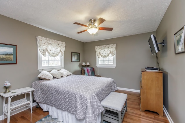 bedroom featuring baseboards, light wood-type flooring, and a textured ceiling