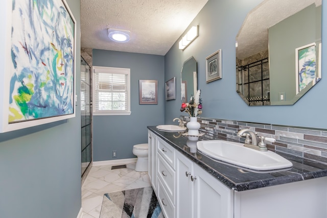 bathroom with toilet, marble finish floor, a sink, a textured ceiling, and a shower stall