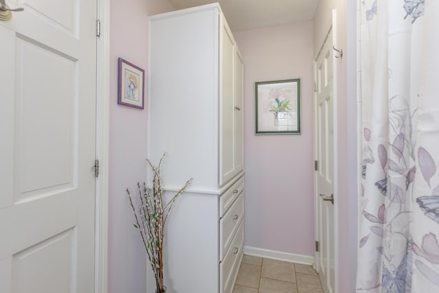 corridor with light tile patterned flooring and baseboards