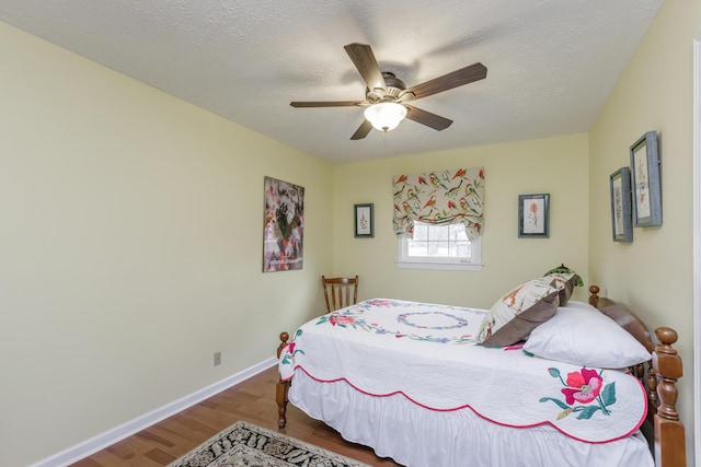 bedroom with ceiling fan, baseboards, a textured ceiling, and wood finished floors