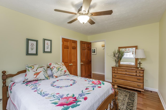 bedroom with a closet, a textured ceiling, baseboards, and wood finished floors