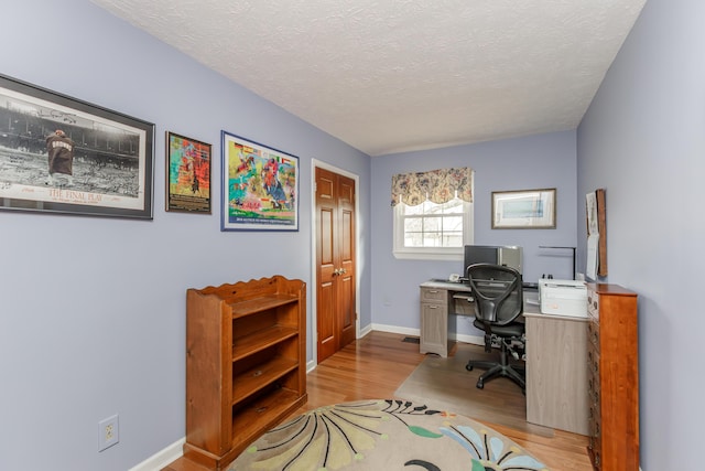 home office featuring a textured ceiling, baseboards, and wood finished floors