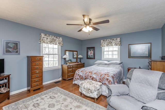 bedroom with multiple windows, baseboards, and wood finished floors