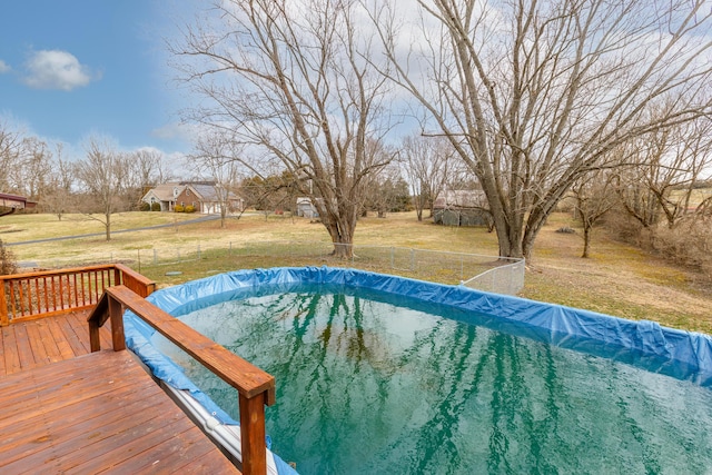 view of pool with a deck, a yard, and fence