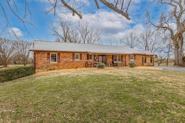 ranch-style house featuring aphalt driveway, brick siding, metal roof, and a front yard