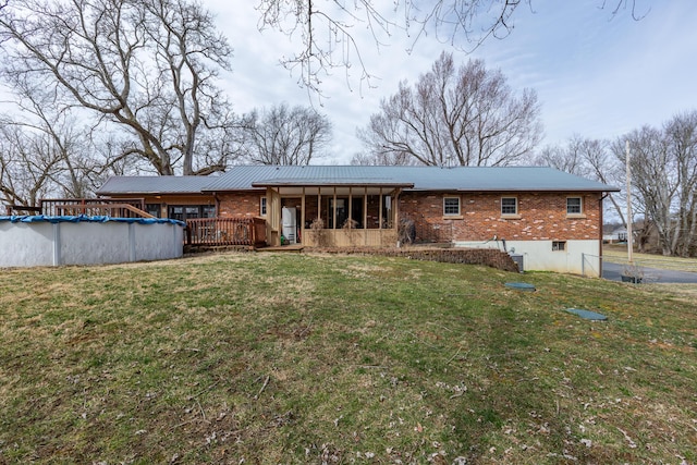 rear view of house featuring a covered pool, brick siding, and a yard