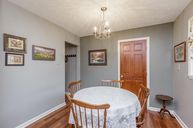 dining area featuring a chandelier, baseboards, and wood finished floors