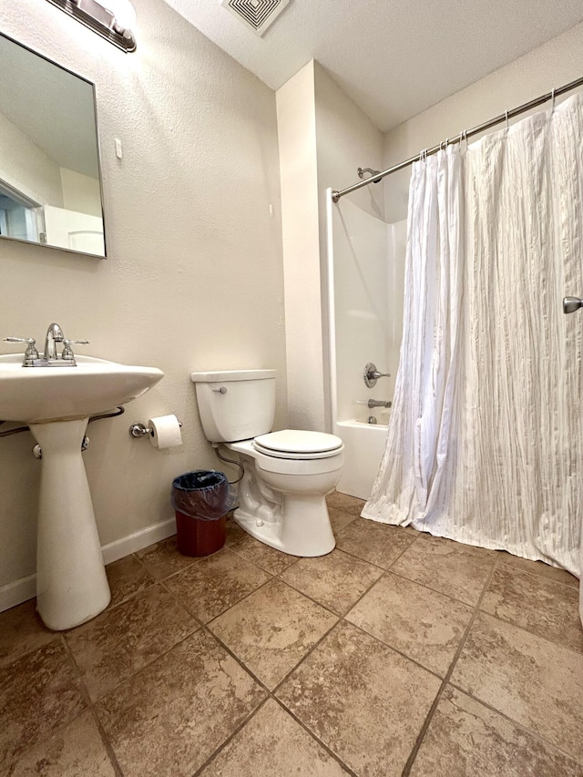 full bathroom featuring visible vents, baseboards, toilet, shower / bath combo, and a textured ceiling