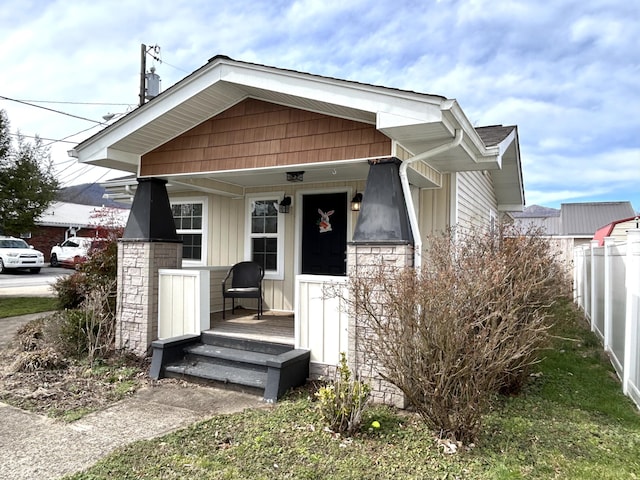 view of front facade featuring a porch, board and batten siding, and fence