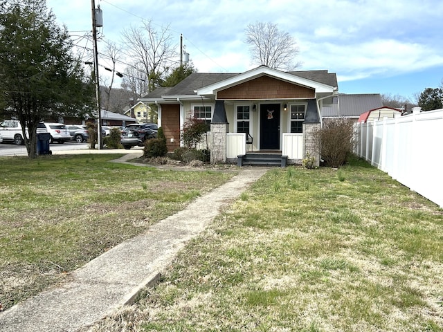 bungalow featuring a front lawn and fence