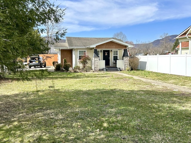 view of front of property featuring a mountain view, board and batten siding, a front lawn, and fence