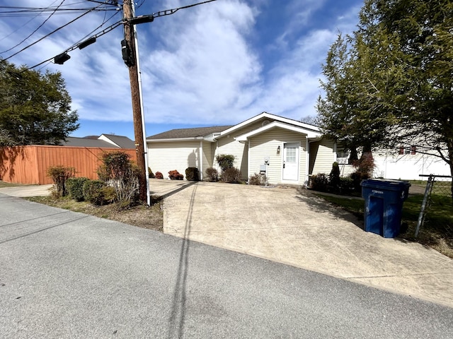 ranch-style home with concrete driveway and fence