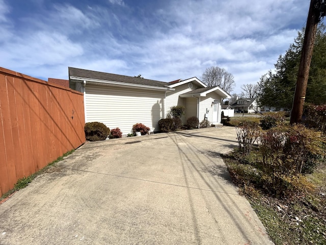 view of side of home with concrete driveway and fence