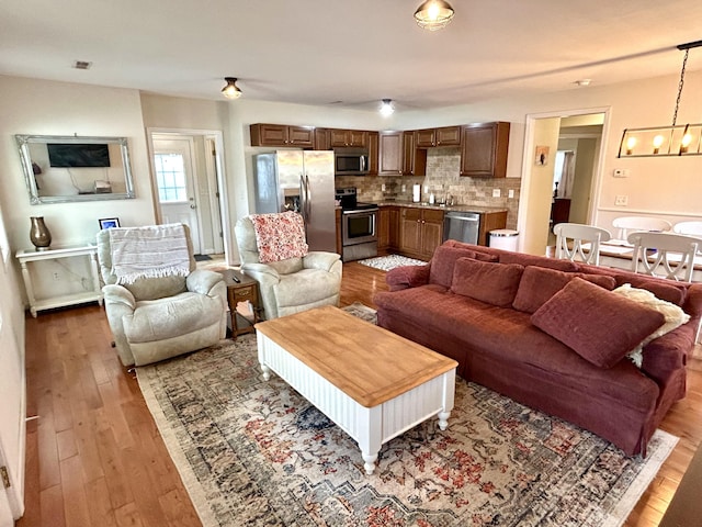 living room with a notable chandelier, visible vents, and light wood-type flooring