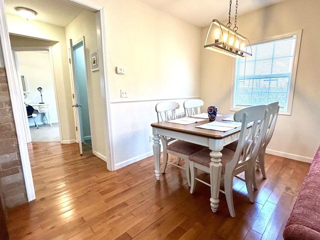 dining room with light wood finished floors, a notable chandelier, and baseboards