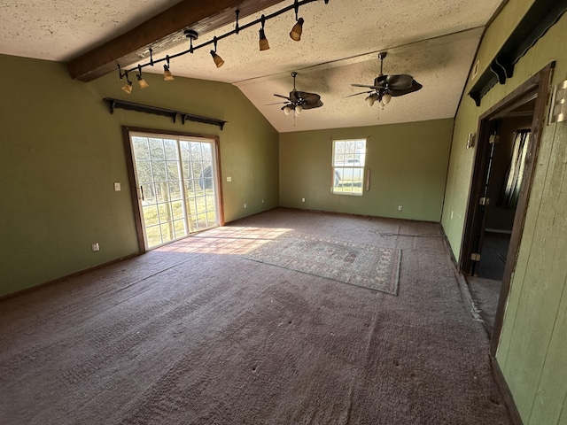 carpeted spare room with baseboards, a textured ceiling, track lighting, and vaulted ceiling with beams