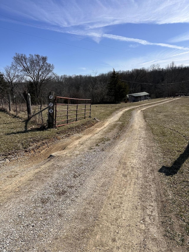 view of street with a gate, a rural view, and a forest view