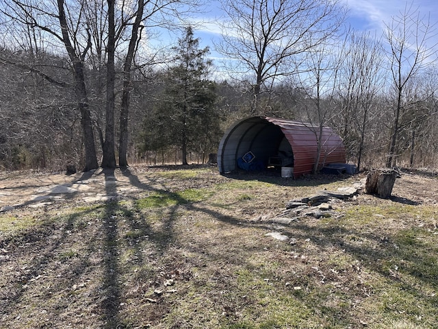 view of yard featuring a carport and a wooded view