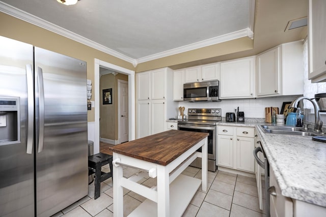 kitchen with ornamental molding, decorative backsplash, appliances with stainless steel finishes, white cabinets, and a sink