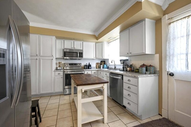 kitchen featuring tasteful backsplash, a sink, stainless steel appliances, and ornamental molding