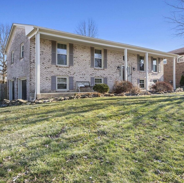 raised ranch featuring a garage, brick siding, and a front yard