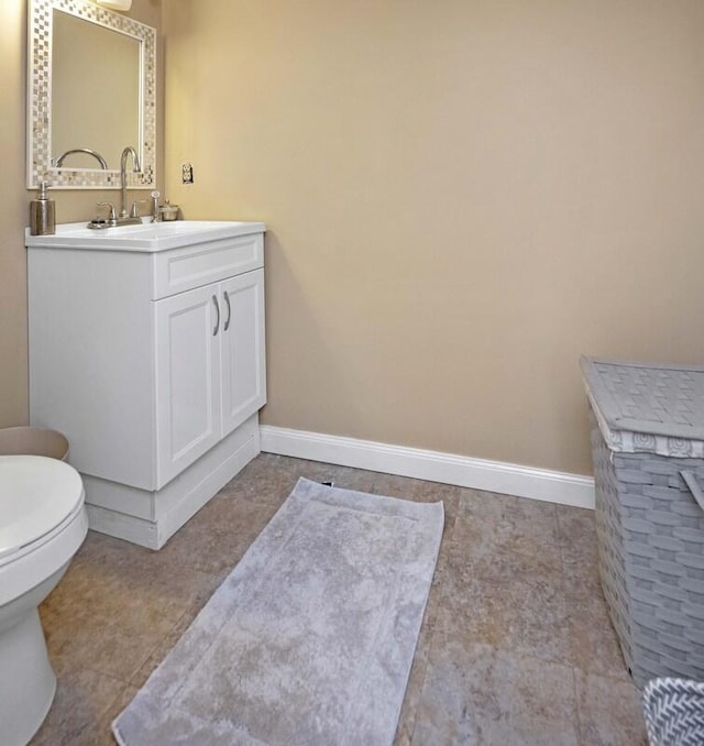 bathroom with toilet, vanity, and baseboards