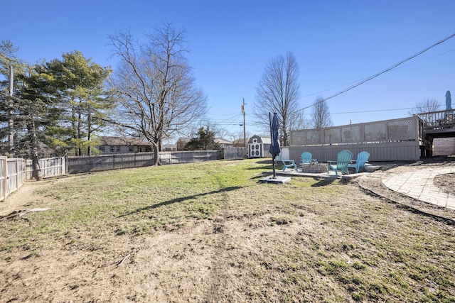 view of yard with a patio, an outdoor fire pit, a fenced backyard, an outdoor structure, and a storage unit