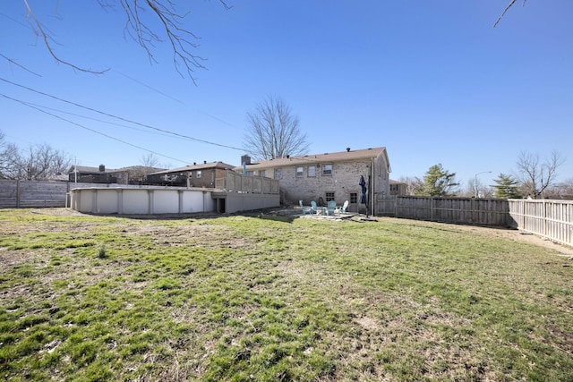 rear view of property featuring a yard, a fenced backyard, and a fenced in pool