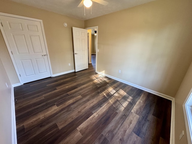 unfurnished bedroom featuring dark wood-type flooring, baseboards, and ceiling fan