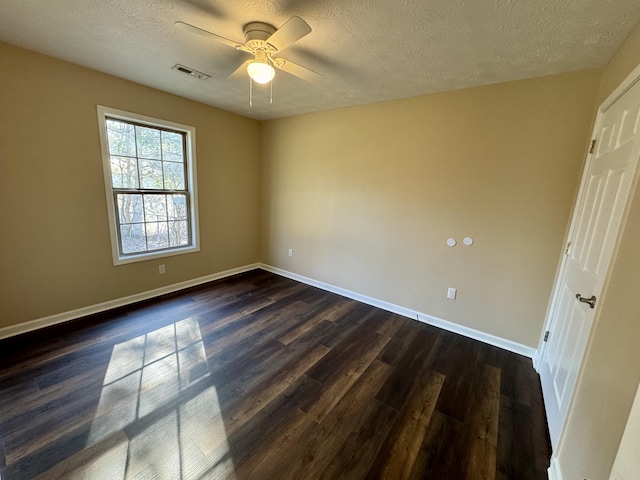 spare room with visible vents, baseboards, a textured ceiling, and dark wood finished floors