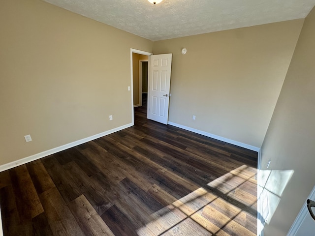 spare room featuring baseboards, a textured ceiling, and dark wood-style floors