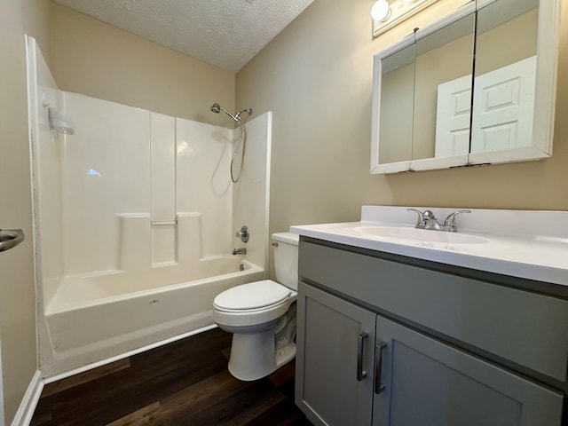 full bathroom featuring vanity, wood finished floors, a textured ceiling, shower / bathing tub combination, and toilet