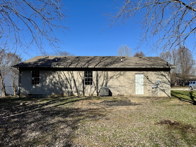 back of house featuring a lawn and roof with shingles