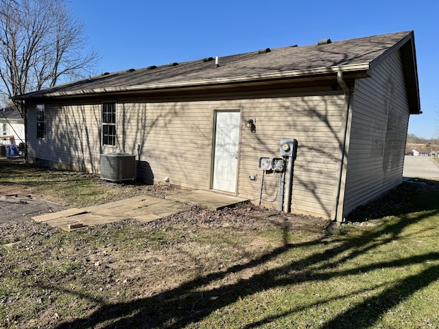 rear view of house with central air condition unit and a yard