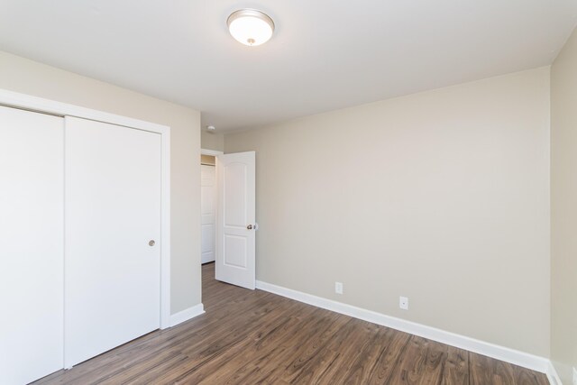 unfurnished bedroom featuring a closet, baseboards, and wood finished floors