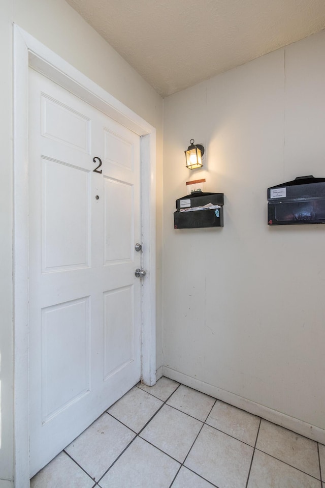 doorway to outside with baseboards and light tile patterned flooring