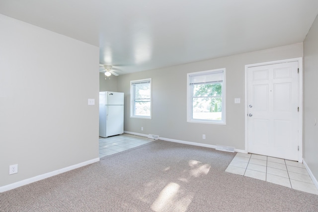 interior space with light carpet, visible vents, baseboards, and light tile patterned flooring