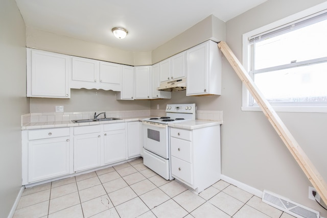 kitchen featuring electric range, visible vents, a sink, under cabinet range hood, and tile counters