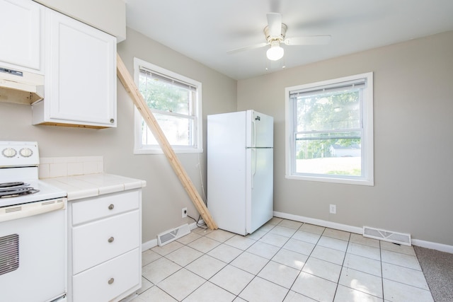 kitchen with under cabinet range hood, visible vents, white appliances, and white cabinetry