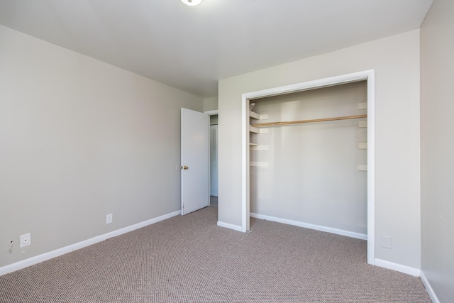 unfurnished bedroom with carpet flooring, baseboards, and a closet