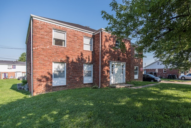 exterior space with brick siding and a lawn