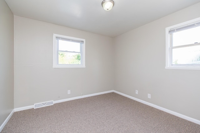 spare room featuring carpet, visible vents, and baseboards