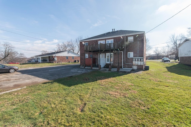 rear view of house with brick siding, a patio area, driveway, and a yard