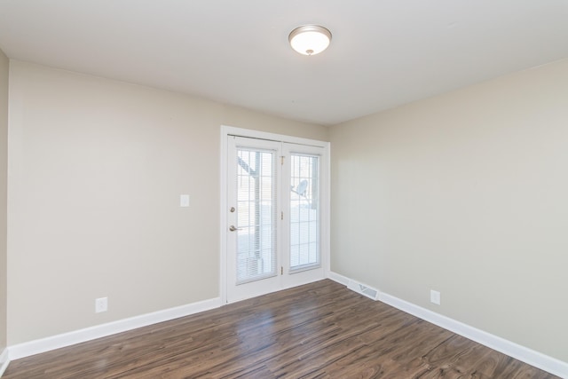 empty room featuring visible vents, baseboards, and dark wood-style flooring